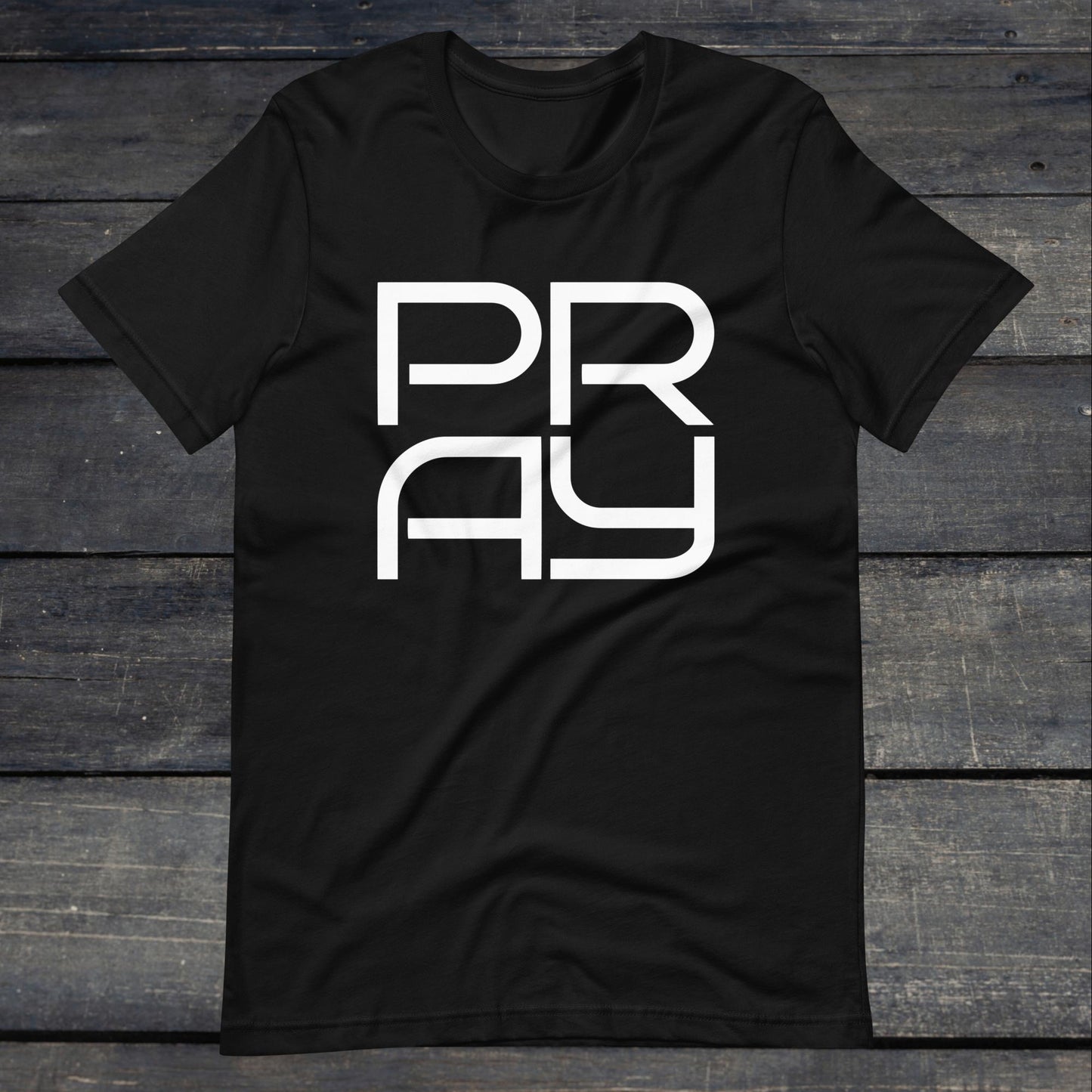 A photo of the Pray 4 Tee. This tee is black with white text that reads P-R-A-Y in large stylish lettering.