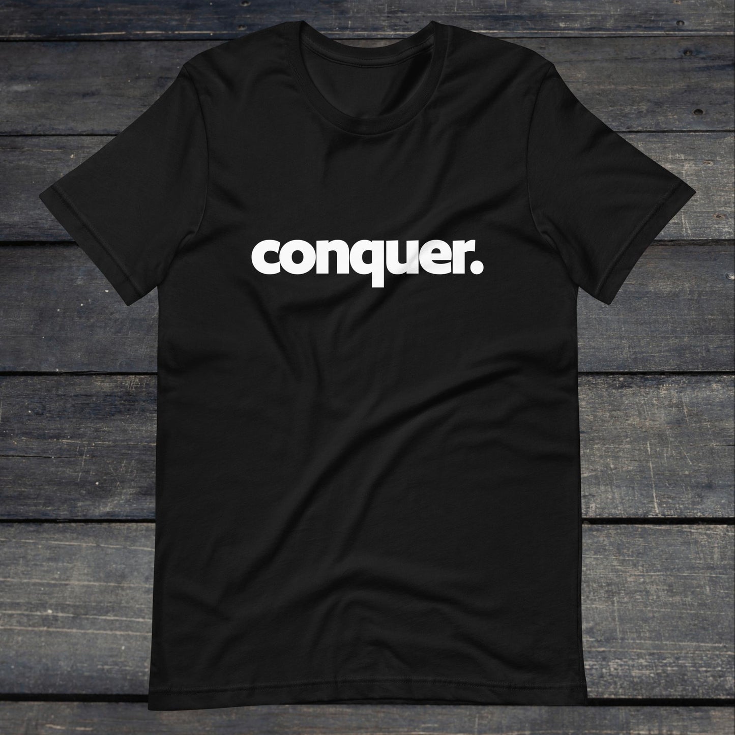 A photo of the Conquer Tee. This tee is black with white text that reads conquer in large bold lettering.