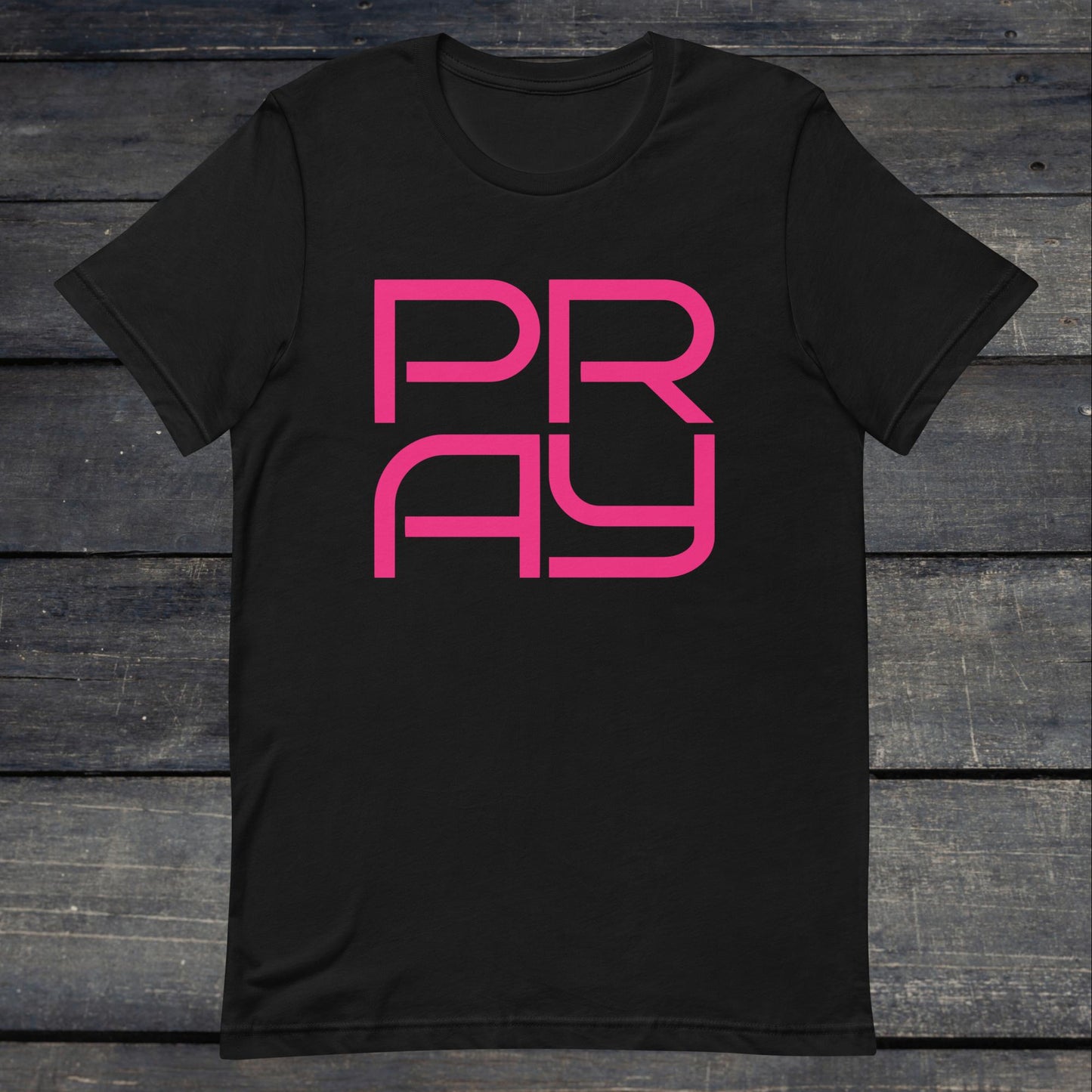 A photo of the Pray 4 Tee. This tee is black with pink text that reads P-R-A-Y in large stylish lettering.