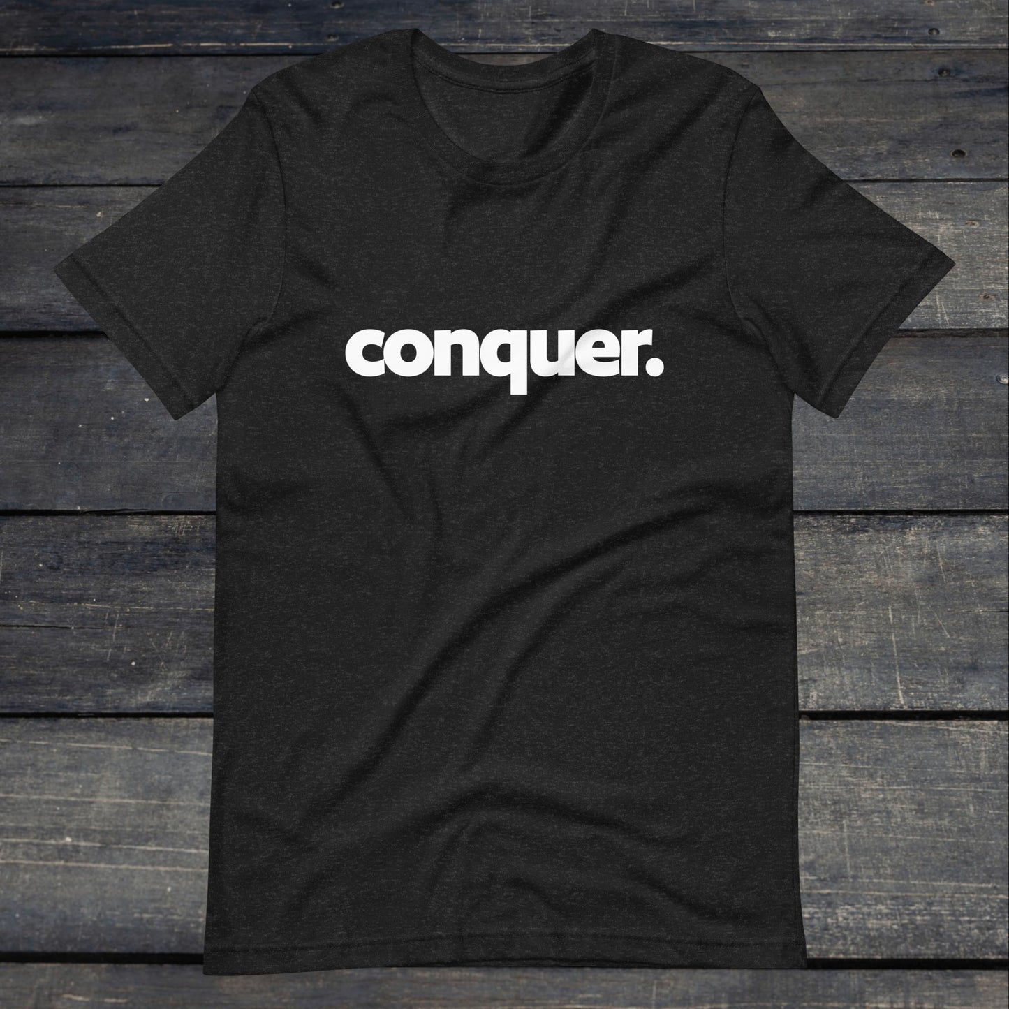 A photo of the Conquer Tee. This tee is heather grey with white text that reads conquer in large bold lettering.