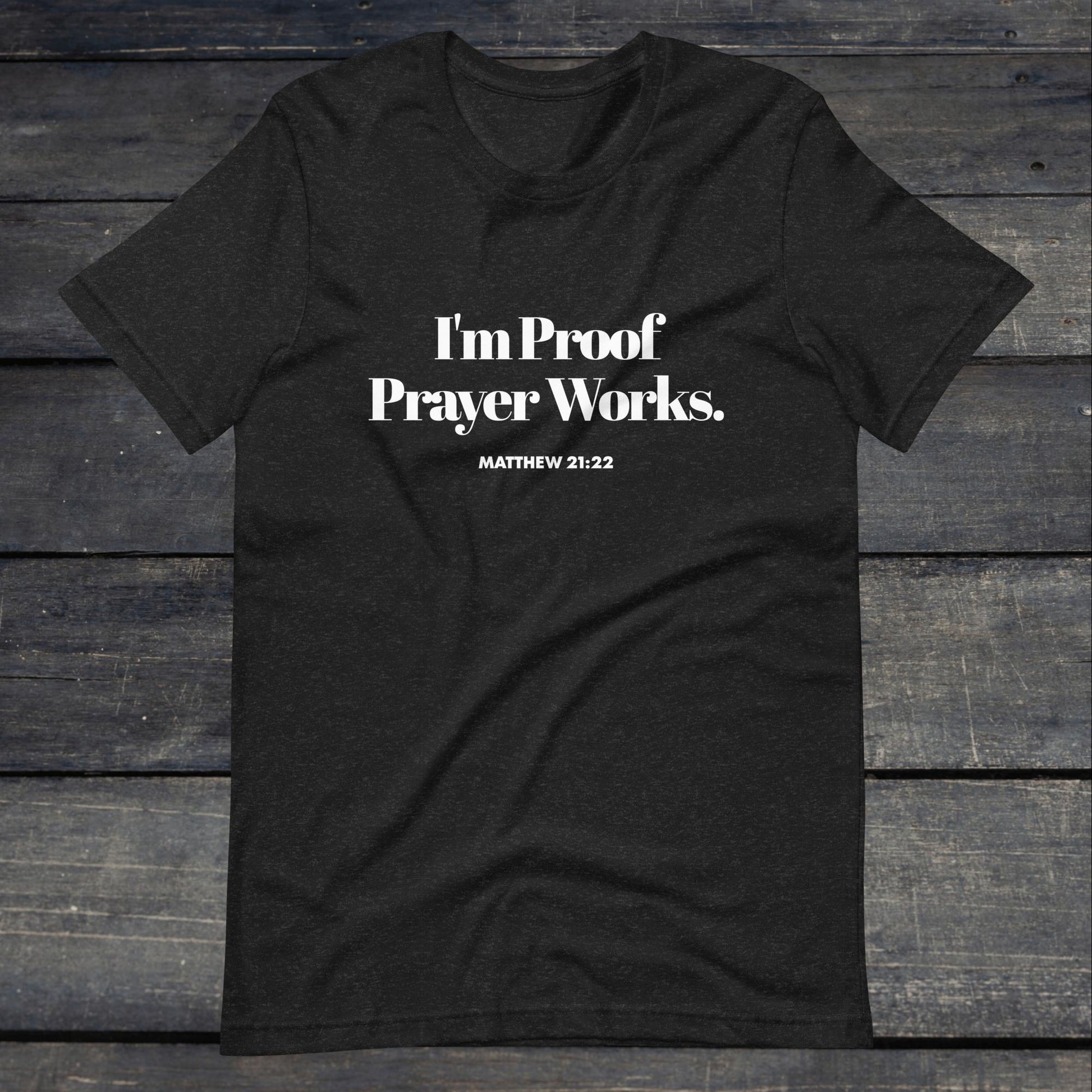 A photo of the "I'm proof prayer works" tee. The shirt color is heather gray with white text that reads "I'm proof prayer works".