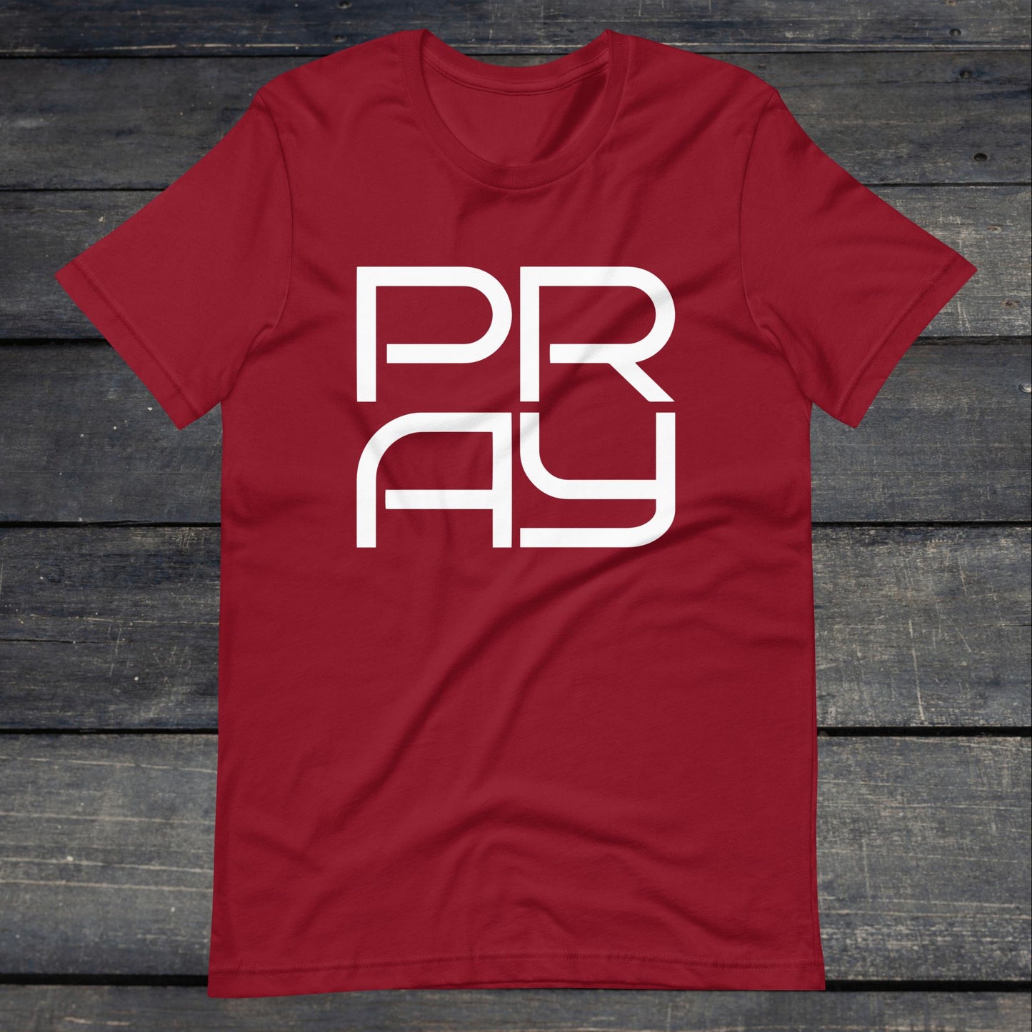 A photo of the Pray 4 Tee. This tee is cardinal red with white text that reads P-R-A-Y in large stylish lettering.