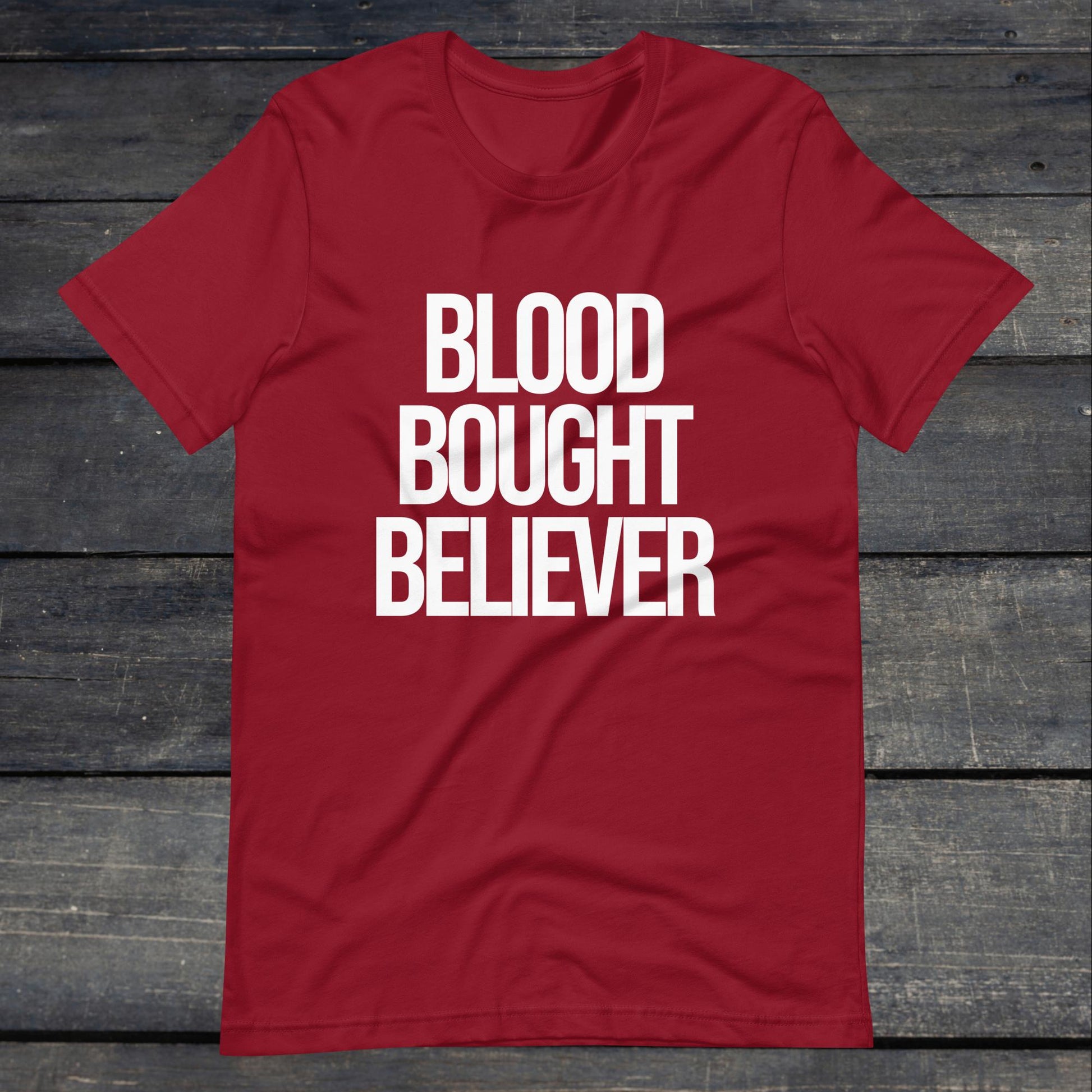 A photo of the Blood Bought Believer Tee. This tee is cardinal red with white text that reads Blood Bought Believer in large bold lettering.