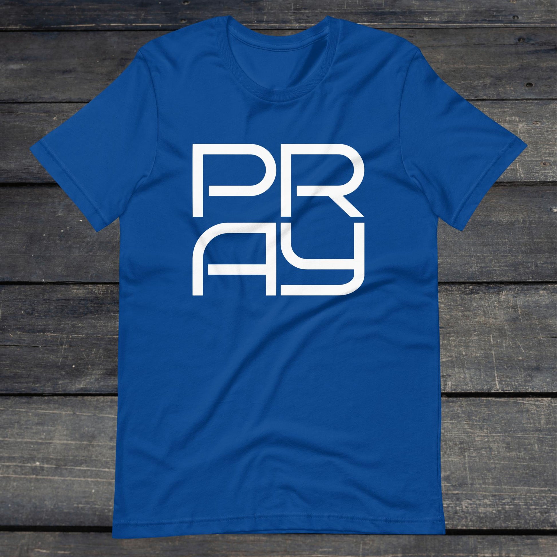 A photo of the Pray 4 Tee. This tee is royal blue with white text that reads P-R-A-Y in large stylish lettering.