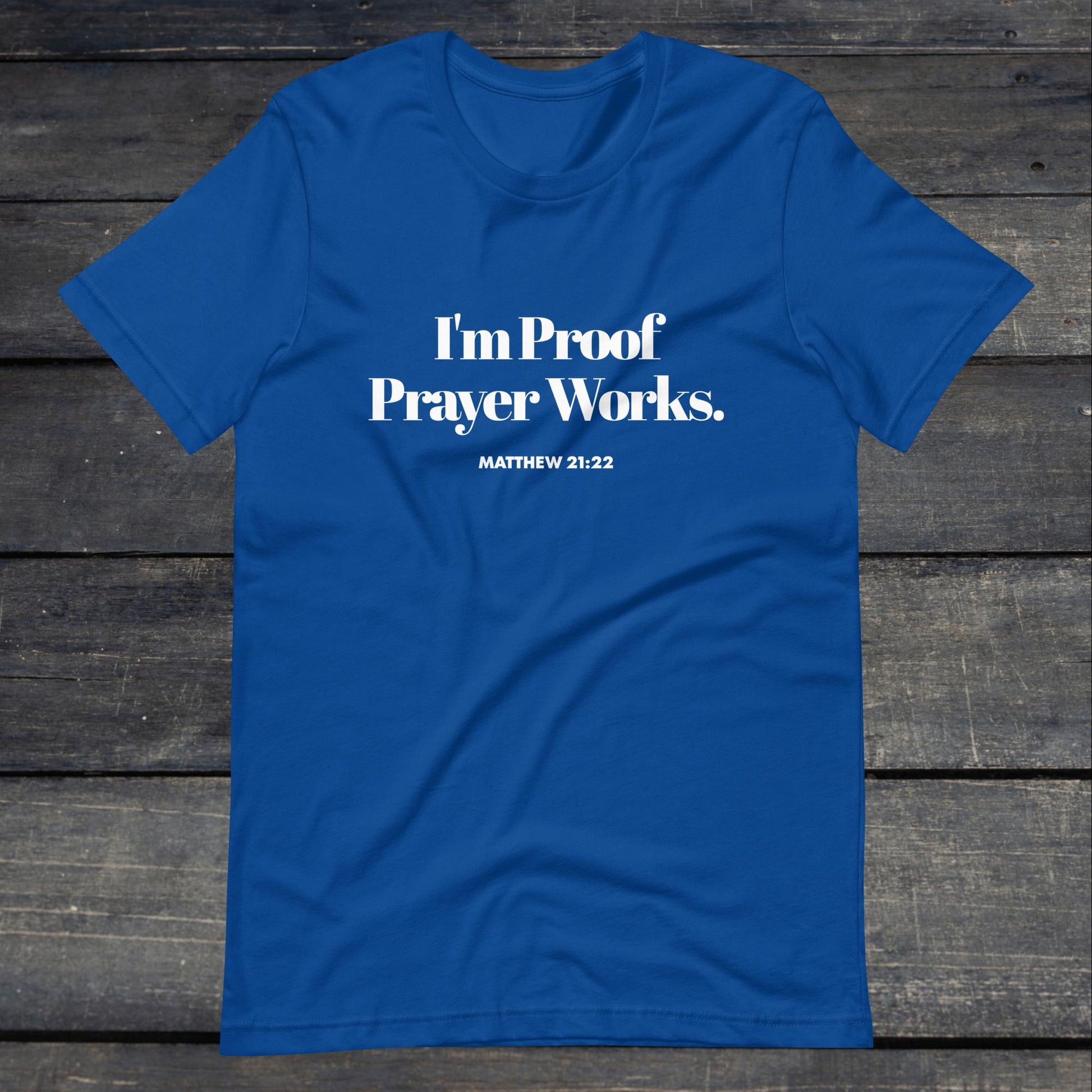 A photo of the "I'm proof prayer works" tee. The shirt color is royal blue with white text that reads "I'm proof prayer works".